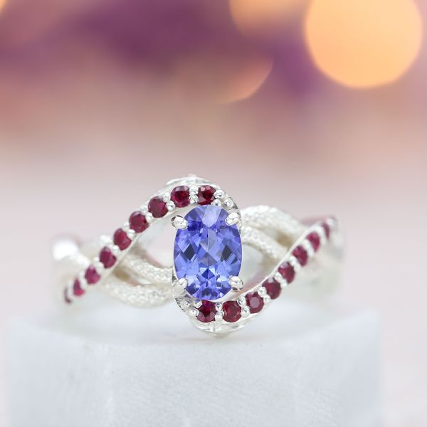 An open spiral of textured metal and accent gems creates a bold setting for the bright, lavender tone of this tanzanite.