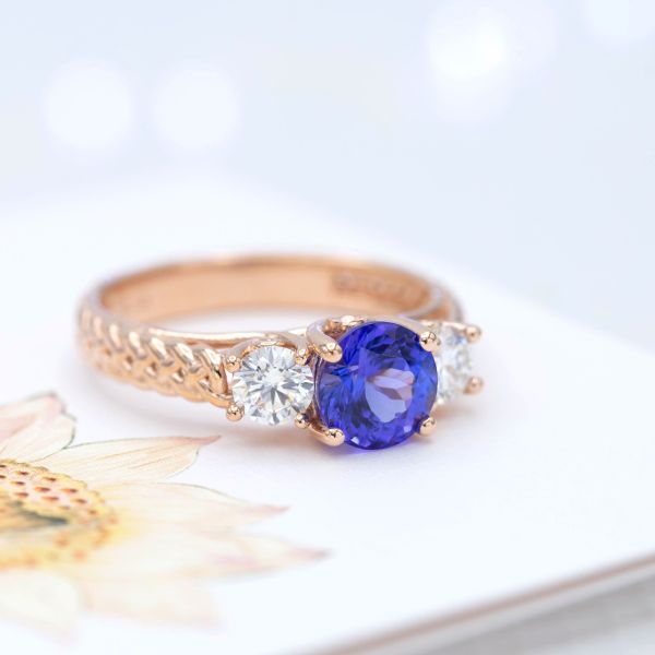 A perfect violet-tinted blue tanzanite center stone pairs with diamonds and braided rose gold in this engagement ring.