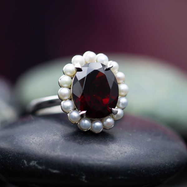 The deep red of Mozambique garnet contrasts beautifully with a floral halo of milky white pearls in this ring.