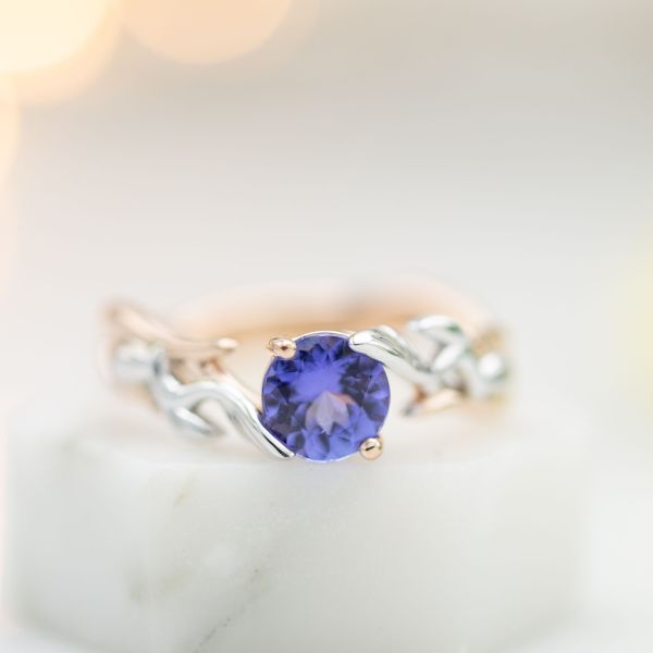 This modern ring mixes two tones of gold in a bypass setting for the purple-blue tanzanite center stone.