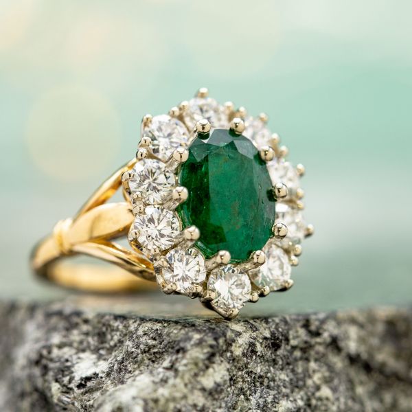 This emerald's deep, kelly green and characteristic fractures fit perfectly in the vintage-themed styling of the engagement ring we designed for it.