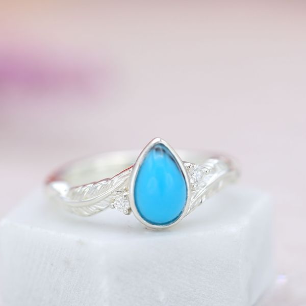 This turquoise has a near-perfect blue with just a single vein to draw the eye. Set in a feather bypass ring.