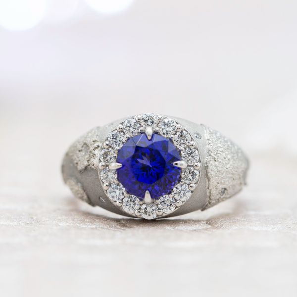 This bold, unique engagement ring surrounds the tanzanite center stone with a globe engraving, reflecting the couple's love of travel.