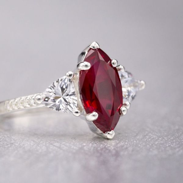 A rich red marquise cut ruby pairs with trillion cut white sapphires a moissanite pave on the delicate band.