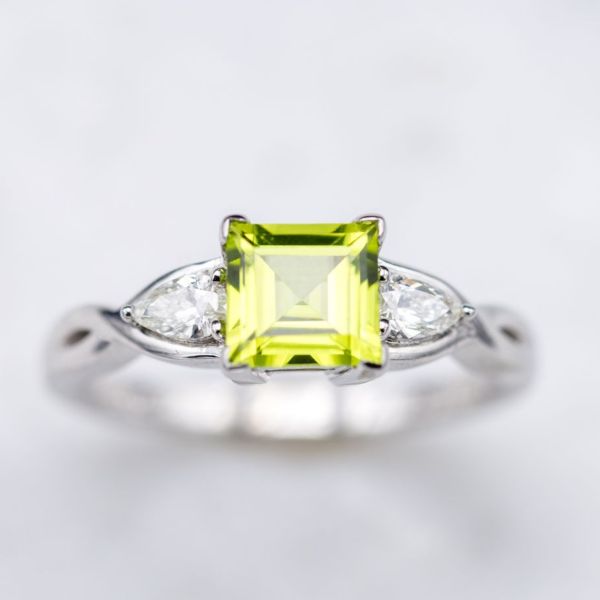 A modern ring with the crisp apple green of peridot flanked by a pair of pear cut diamonds.