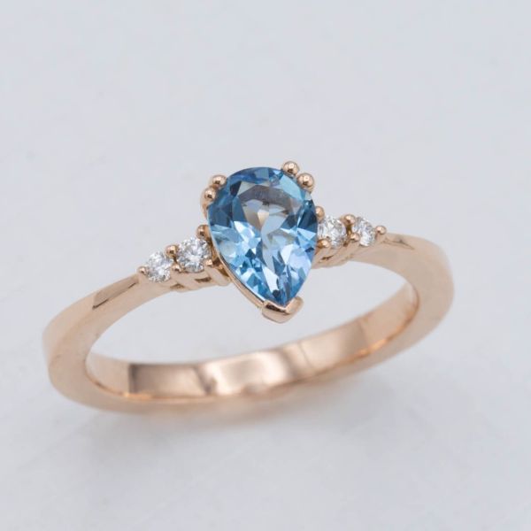 A delicate rose gold band with a reverse taper from the pear cut aquamarine center stone.