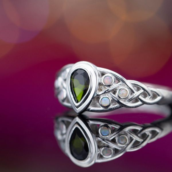 A Celtic ring with a deep green tourmaline (pear cut) surrounded by white opal accents.