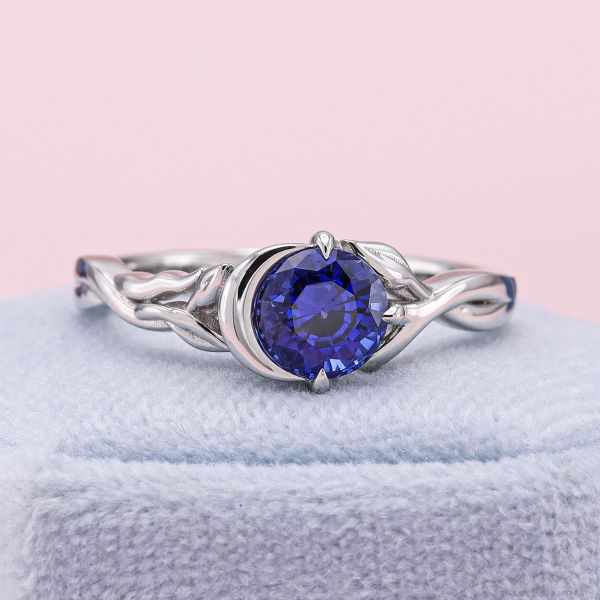 We chose a deeply saturated lab-created sapphire to pull double shifts as a blue-black night sky and deep blue enchanted lake. Both settings come to mind in this sapphire and platinum ring, with a crescent moon hugging one side of the stone and vines crawling up the other.