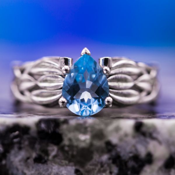 Pear cut sky blue topaz set in a white gold shank with layered leaf detailing.