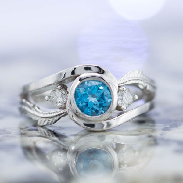 Inspired by the game Harvest Moon, in which a blue feather is given as symbol of a marriage proposal. Our design features delicate white gold feathers and a Swiss blue topaz to bring in the blue.