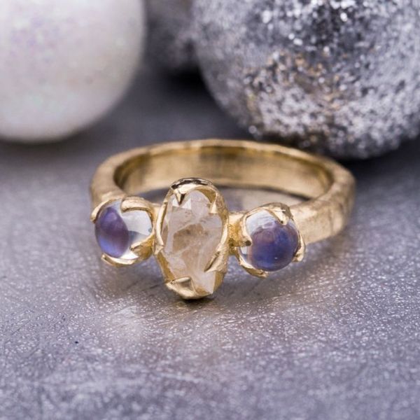 This ring uses smooth, shimmering rainbow moonstones to contrast the raw quartz and hammered texture of the band.